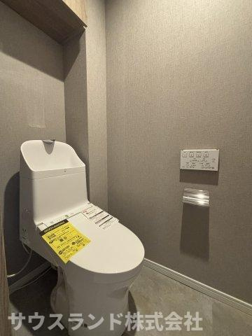 深みのある内装でまとめた独立トイレ。温水洗浄便座と壁付け操作パネルを備え、必要な機能をコンパクトに配置しています。白い設備が空間に明るさを添え、すっきり使える落ち着いた仕上がりです。
