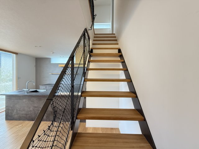 リビングから続くデザイン階段は、ブラックのアイアン手すりが空間を引き締めるアクセントに。抜け感のある構造で圧迫感がなく、開放的なLDKをより広く感じさせます。階段を通じて上下階のつながりが生まれます。