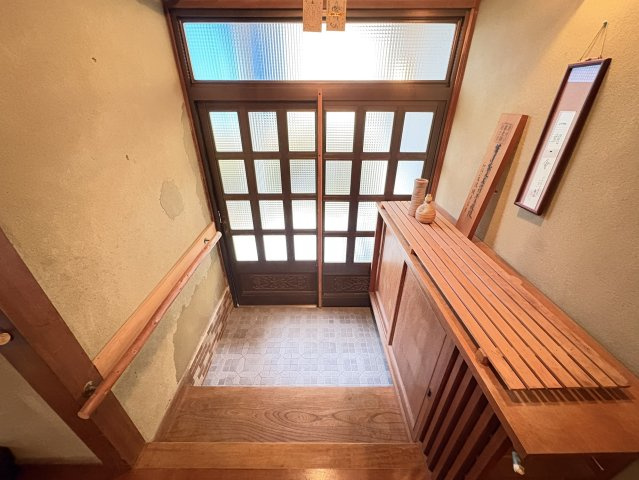 木製の格子扉と下駄箱が印象的な、温かみある玄関スペース。手すり付きで段差の昇降も安心。来客を迎える場としても趣があり、和の雰囲気を大切にした空間です。収納力のある下駄箱は靴の整理にも便利ですね。