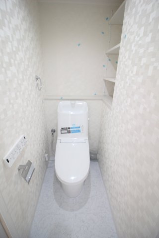 温水洗浄便座付きのトイレ。壁面には使いやすい棚が設けられています