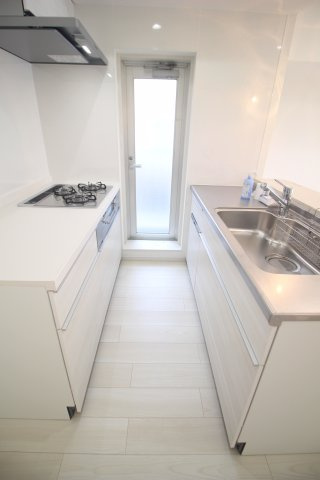 コンロと流しが向かい合わせになったセパレートタイプの？型キッチン。扉の向こうはバルコニーです