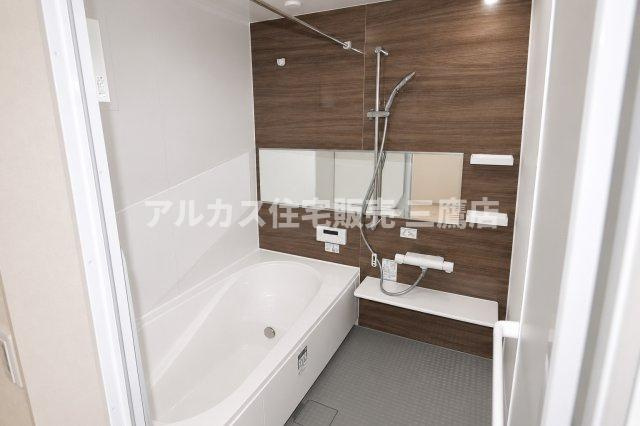 木目調パネルが落ち着きを添える浴室。横長ミラーと浴室物干しバーを備え、使い勝手にも配慮されています。　