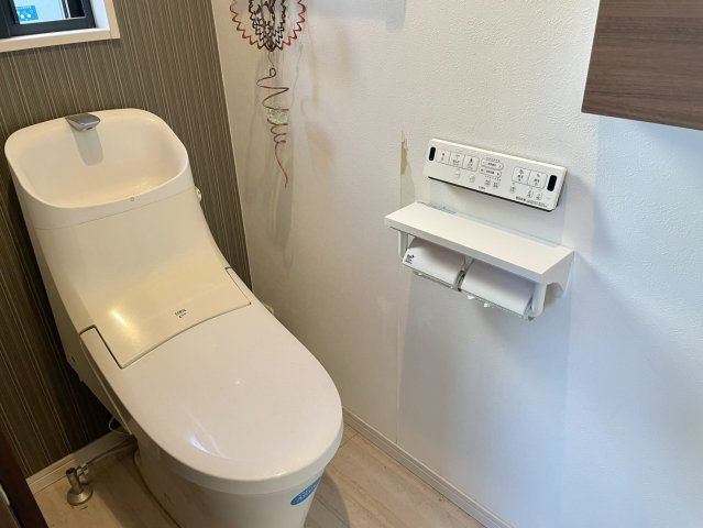 落ち着いた色合いのアクセントクロスが上質さを感じさせるトイレ空間。手洗い一体型で省スペースながら使い勝手◎。窓があるため換気もしやすく、清潔を保ちやすい点も特徴。温水洗浄便座などの機能も整っております