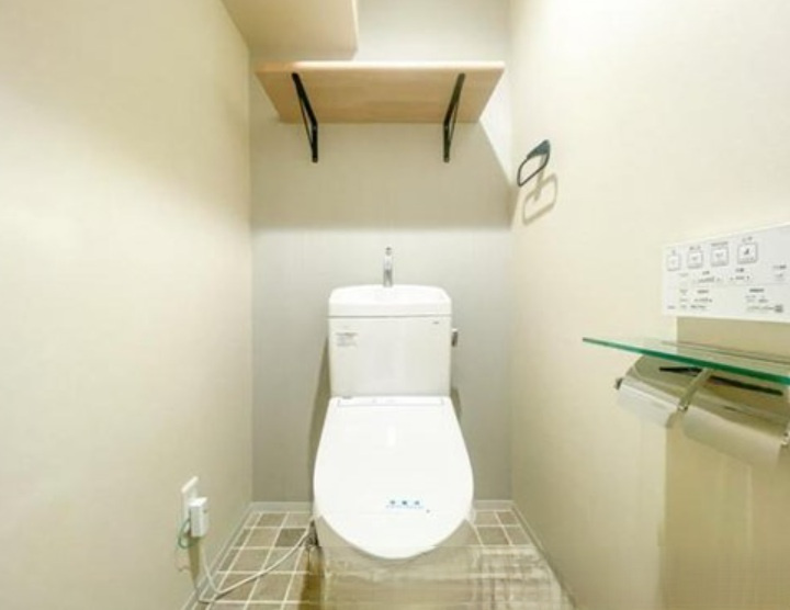 広いトイレには収納棚があり、清潔感のある空間ですね。