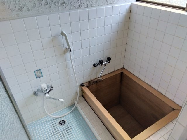 窓があるので明るい室内です。木のオシャレな浴槽です。白いタイルが清潔感があります。　