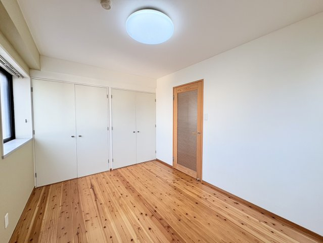 明るい色合いの壁と木目のフローリングが調和した、落ち着きのある洋室です。壁面には複数の収納スペースを備えており、衣類や日用品などを分けて整理しやすく、家具を配置できる壁面も確保できるのもポイントです。