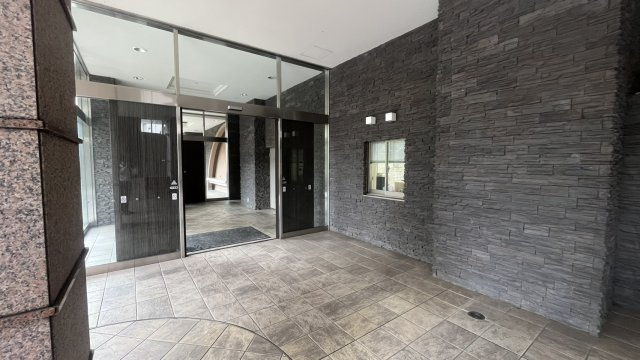 重厚感のある石調の壁面が印象的なマンションエントランス。落ち着いた色合いで統一され、住まいの入口にふさわしい上品な雰囲気です。屋根のあるゆとりあるスペースが確保され、雨天時の出入りにも配慮されています