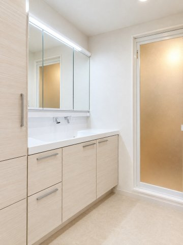 広々としたサイズの洗面台＋収納棚。タオルだけでなく、浴室のストック品などもたくさん収納が出来ます。三面鏡の裏にも収納が可能です。※画像はAI加工で家具・小物を消去しています。