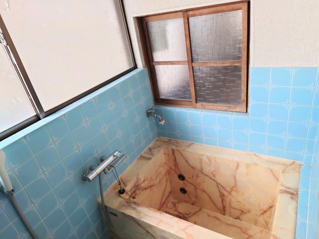 大理石調のおしゃれなバスタブ。ノスタルジックなタイルや小窓と相まって癒しの空間に。