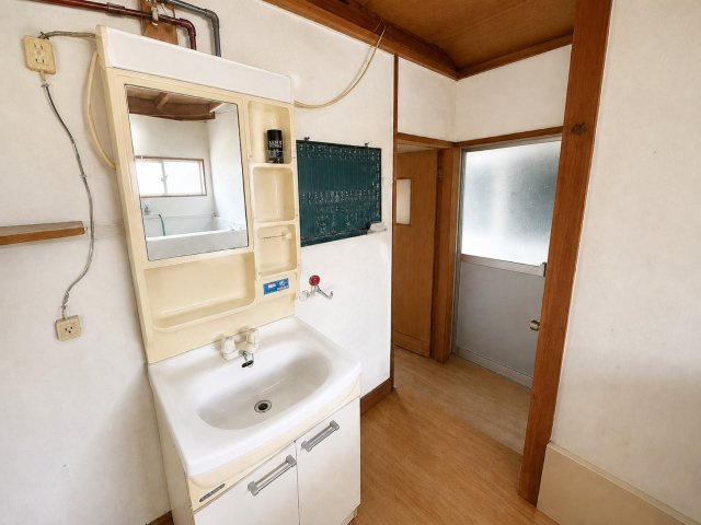 照明付き鏡を備えた独立洗面化粧台。横に洗濯機用蛇口を配置。