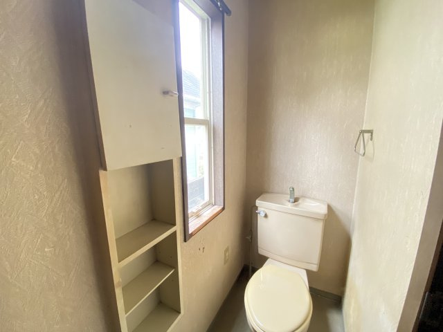 窓付きで自然光が入る明るいトイレは換気もしやすく清潔感のある空間です。手洗い付きタンクを採用し、コンパクトながら機能性も兼ね備えています。壁面には収納棚があり、トイレットペーパーや小物の整理に便利です