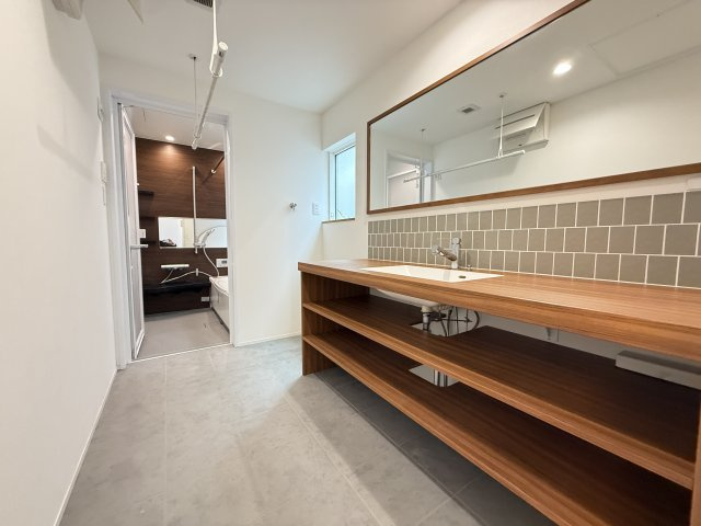 ホテルライクな雰囲気の洗面スペースは、広々としたカウンターと大きな鏡が特徴。収納棚も備わっており、タオルや日用品をすっきり整理できます。朝の身支度も快適に行えるゆとりある空間設計です。　