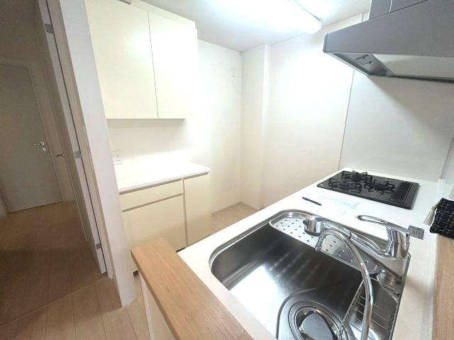3口コンロと広々シンクでお料理も快適。背面に収納棚が備え付けられており、スッキリ片付くキッチンです。