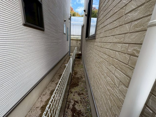 建物と隣地の間にはしっかりとしたスペースが確保され、通気性も良く湿気がこもりにくい環境です。境界フェンスが設置されているため安心感があり、メンテナンスや点検の動線としても十分な幅があります。
