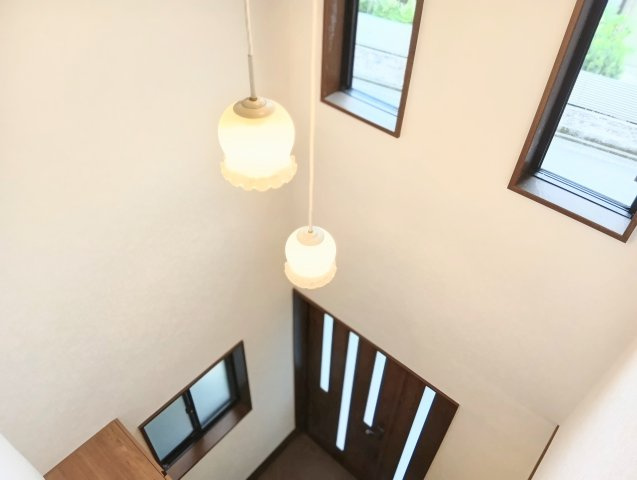 玄関に入った瞬間、天井まで広がる吹抜けがゆとりを演出。ペンダントライトが上品な空間に。
