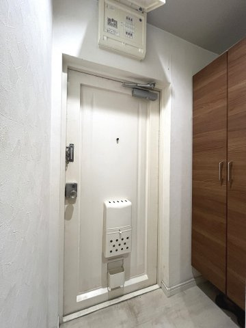 白基調の玄関に木目のトール収納を設置。明るく清潔感のある空間です