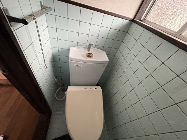 レトロな淡いブルーのタイルが温かみのある雰囲気をつくり、落ち着いて利用できるトイレ空間です。手洗い一体型のトイレで節水にも配慮されており、使い勝手も良好。窓付きのため換気がしやすいのも嬉しいポイント。