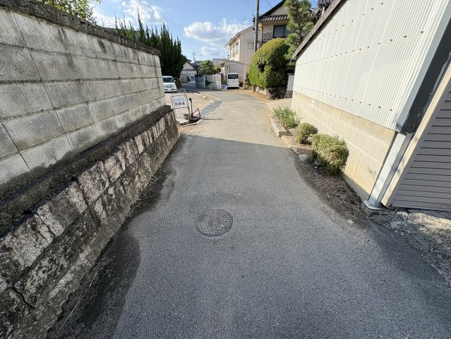 西側の前面道路。南西向きの接道で陽当たり良好。リバーサイドの穏やかな雰囲気に包まれた立地です。近隣にはコンビニや商業施設が点在し、買い物や通院も便利。静かな住環境と生活利便性のバランスが取れた土地。