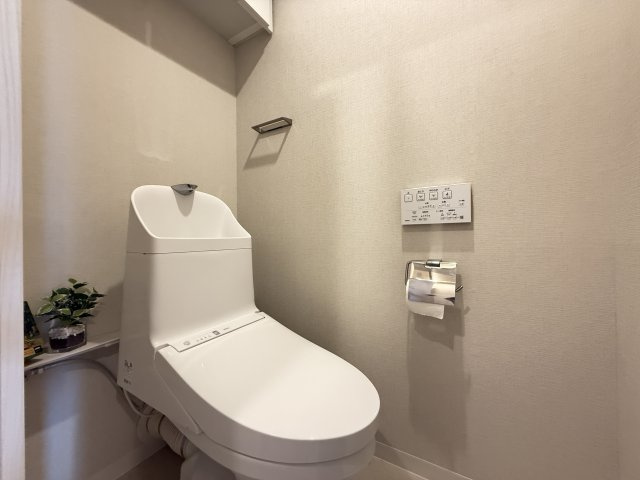 すっきりとした内装でまとめられた清潔感のあるトイレ。温水洗浄便座を備え毎日快適に使用できます。壁面には操作パネルやペーパーホルダーを配置。落ち着いた色合いのクロスがやさしい雰囲気を演出し使いやすい空間