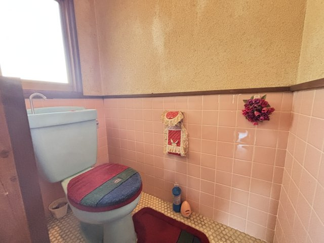 窓付きで換気がしやすいトイレ空間になっております。優しいピンクのタイル張りの内装がレトロな雰囲気を演出しています。　コンパクトながらも使いやすい配置で、日常使いに配慮された設計です。　