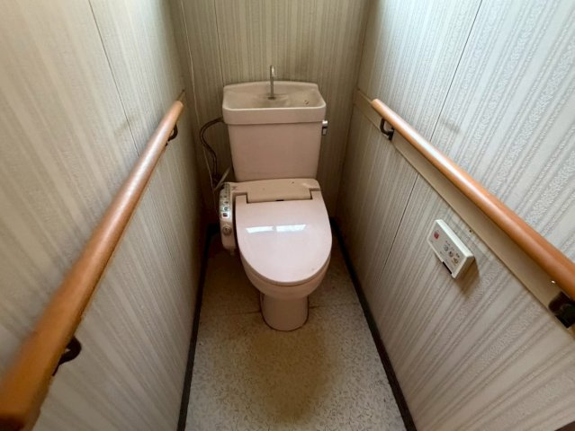 ウォシュレット付きトイレ。手すり完備でバリアフリー対応。シンプルで清潔感のある空間。