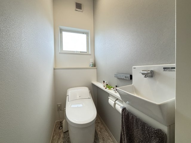 窓から自然光が差し込む、明るく清潔感のある1階トイレです。温水洗浄便座を備え、毎日快適にご利用いただけます。シンプルで落ち着いたデザインで、お客様用としても気持ちよくお使いいただける空間です。