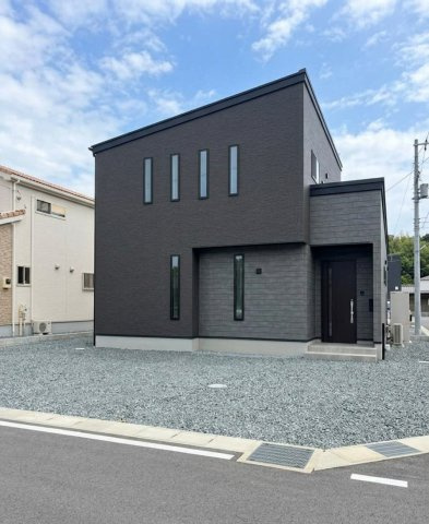 片流れ屋根が目を引くモダンな佇まい。ダークトーンの外壁をベースに、素材感の異なるグレーを組み合わせた、立体感のあるデザインです。縦長のスリット窓が、アクセントとしてシャープな印象を引き立てます。