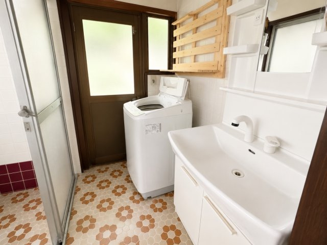白を基調とした洗面室は、明るく清潔感のある印象。大きな洗面化粧台と収納付きで、身支度用品をすっきり整理できます。洗濯機置場や勝手口も備え、家事動線に優れた使い勝手の良い水回りです。　