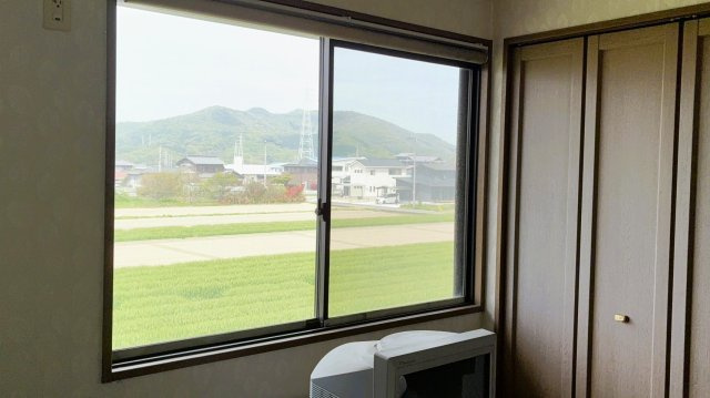 大きな窓から緑豊かな田園風景と山並みを望む、開放感ある眺望。