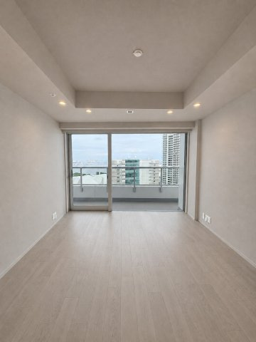 大きな開口部から開放的な湾岸の景色を望む、明るいリビングダイニング。木目調の床と折り上げ天井のダウンライトがモダンな空間を演出します。バルコニーへ繋がるフラットな視線が心地よいレイアウトです。