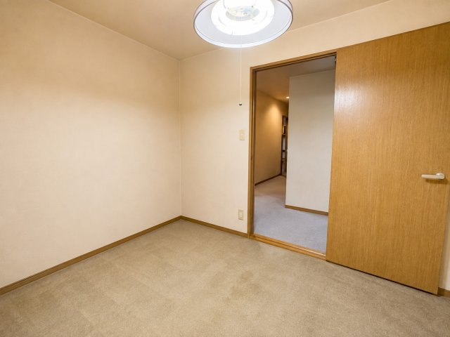 木目調の建具が温かみを添える5.3帖の洋室。明るい色合いの壁と落ち着いた床材で、シンプルながら居心地のよい空間です。寝室や子ども部屋、書斎など、暮らし方に合わせて多目的に利用可能です。