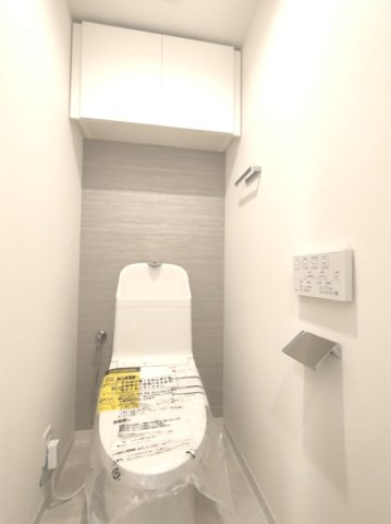 【トイレ】　温水洗浄便座・壁付けリモコン付き。吊り戸棚を備えた機能的なトイレです。