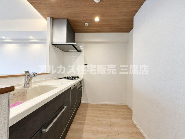木目調の折り上げ天井クロスがアクセントになった、落ち着きのあるシックなデザインの対面式キッチンです。