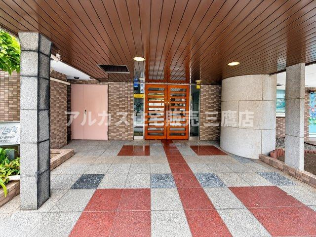 赤と白のタイル床や木目調の天井が印象的な、温もりを感じさせるエントランスアプローチです。　