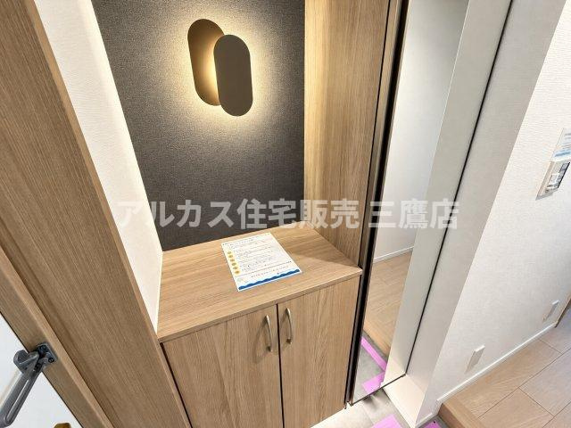 おしゃれなアクセント照明と壁面が上品な雰囲気を演出する、すっきりとした玄関収納スペースです。