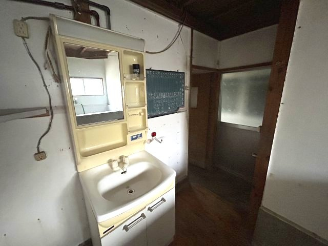 照明付き鏡を備えた独立洗面化粧台。横に洗濯機用蛇口を配置。