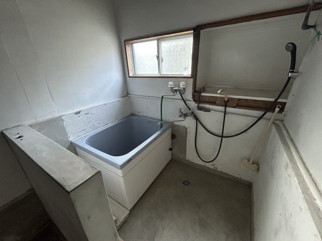 換気窓を備えた浴室。装飾のないシンプルな深型の浴槽を採用