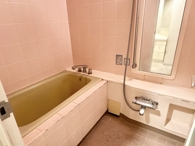 ピンク色のタイルが印象的なお風呂場は、温かみを感じさせる魅力的な空間です。タイル張りの床と壁は、清潔感を維持しやすく、落ち着いた入浴空間を提供します。浴室洗面台があり、物を置いたりと便利に使えます。