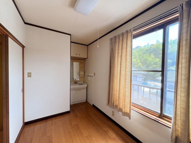 窓の外には周辺の緑や住宅街が広がり、室内にいながら自然を身近に感じられるのも魅力。窓を開けることで風を取り込みやすく、心地よく過ごせます。洗面スペースがあり、寝室や個室として使いやすい一室です。