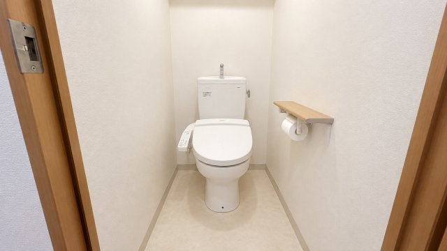 白を基調とした清潔感のあるトイレ空間。温水洗浄便座を備え快適に使用できます。ペーパーホルダー上部には棚が設けられており小物などを置くスペースとしても便利。シンプルで落ち着きのある内装に仕上がっています