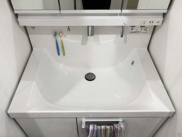 三面鏡付きの洗面化粧台を採用しており、鏡裏収納には洗面用品や化粧品、歯ブラシなどをすっきり収納できます。シャワー水栓付きで洗髪や洗面ボウルのお手入れもしやすく、毎日の身支度を快適にサポートします。
