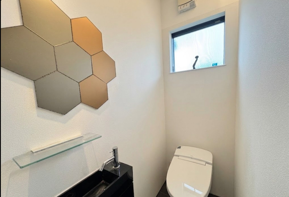 シンプルながらデザイン性を感じられるトイレ空間。手洗いスペースが設けられており、来客時にも使いやすい仕様です。壁面デザインが空間に個性をプラスし、注文住宅ならではのおしゃれな雰囲気を演出しています。