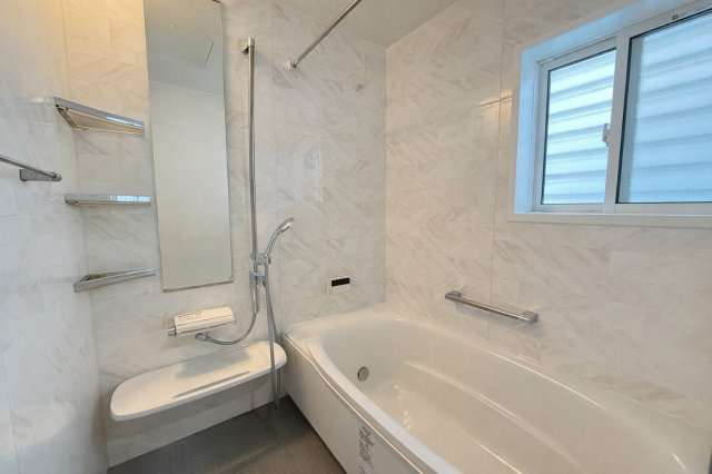 落ち着いた色合いの壁面が上質感を演出する浴室。窓付きで換気がしやすく、湿気対策にも配慮されています。ゆったりとした浴槽で一日の疲れを癒せる空間。手すりも設置され、安全面にも配慮された仕様です。　