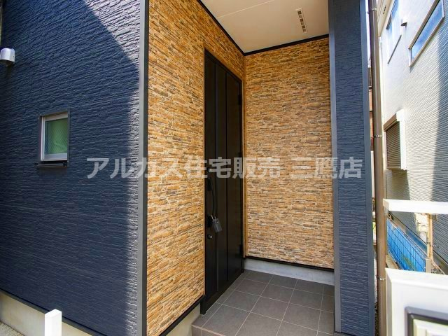 石調の外壁とブラックの玄関ドアが調和する玄関まわり。屋根付きで落ち着いた印象です。　