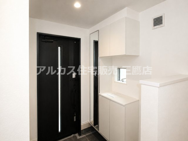 姿見と上下のシューズ収納を備えた玄関。小窓付きで、身支度や靴の整理がしやすい空間です。　