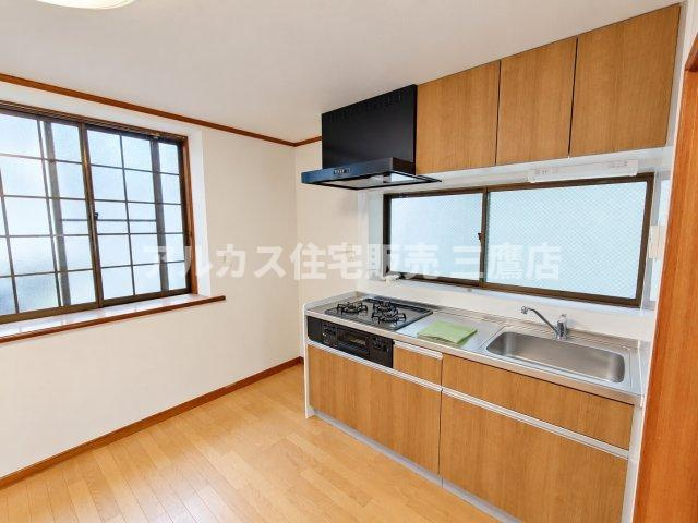 明るく清潔感のある壁付けキッチン。正面や側面に窓があり換気・採光も良好で、吊戸棚などの収納スペースも充実しています。