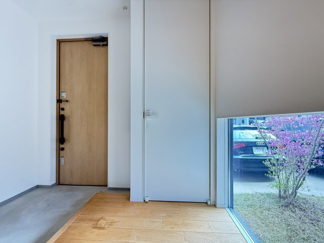 大きなFIX窓から自然光が差し込む明るい玄関空間。外の緑も感じられ、開放感のある心地よい第一印象を演出します。シンプルで洗練されたデザインにより、帰宅時も来客時も気持ちよく迎えられる空間です。