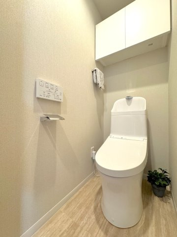 【トイレ】清潔感あふれる温水洗浄便座付きトイレ。上部にはトイレットペーパーや掃除用品をすっきり収納できる便利な棚を備えており、空間を広々と清潔に保てます。