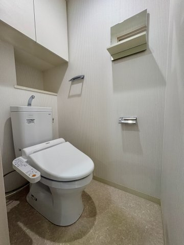 節水型温水洗浄便座。カウンターと吊戸棚を備え、トイレットペーパーや掃除用品などをすっきり収納できます。