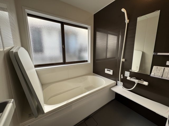 落ち着いたブラウンパネルが高級感を演出する浴室。　追い焚き機能付きで、いつでも快適な温度のお風呂を楽しめます。　大きな窓から光が差し込み、換気もしやすく清潔を保てる癒しのバスルームです。